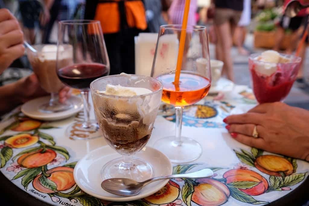 A table covered with half-eaten granita and cream, and several cocktails.