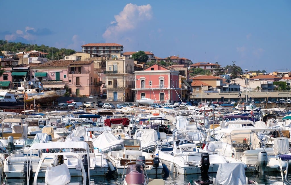 Rows of boats in front of the pastel village of Aci Trezza