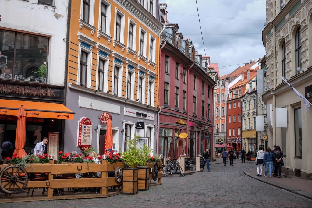 A narrow street in Riga lined with orange and pink buildings.