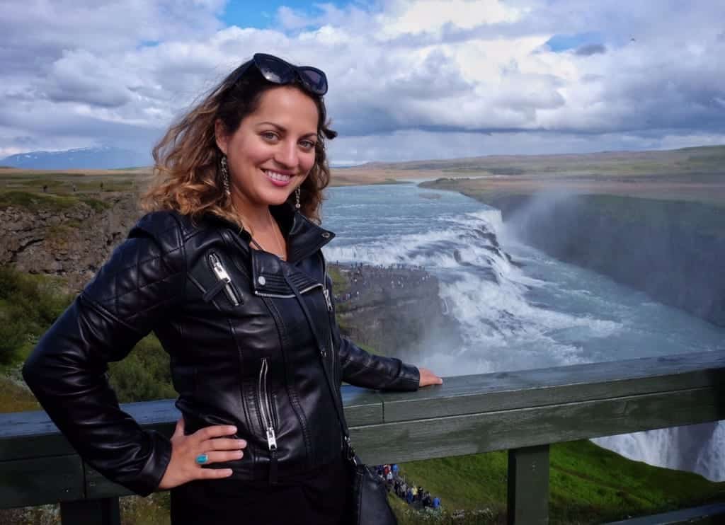 Kate in a leather jacket standing in front of Gulfoss waterfall in Iceland.
