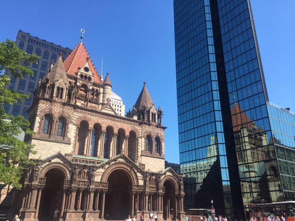 The church on Copley Square, Boston, a stone building with a red top, next to the glassy modern John Hancock tower in Back Bay, Boston.