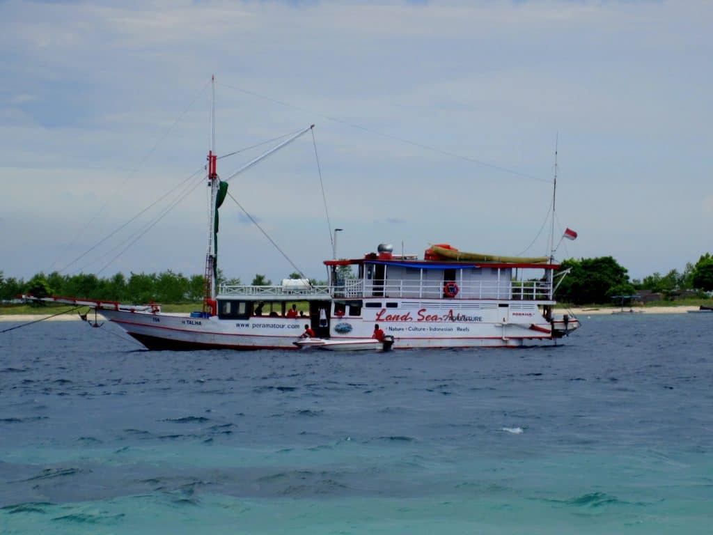 A small wooden boat anchored off shore in a turquoise sea