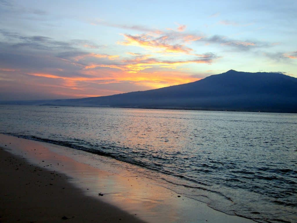 A pink and blue sunset on a white sand beach in Indonesia