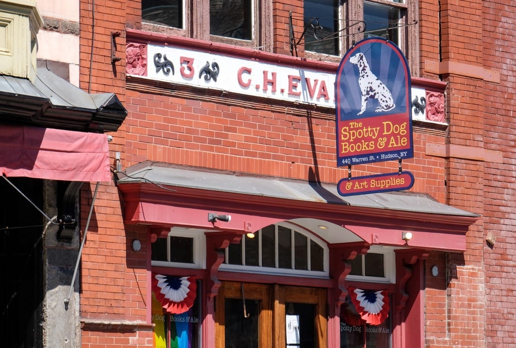 A brick building with a sign reading The Spotty Dog Books & Ale with a Dalmatian on it.