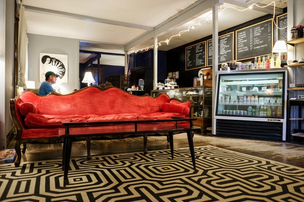 A coffee shop with an ornate red setee on a black and white geometric rug.