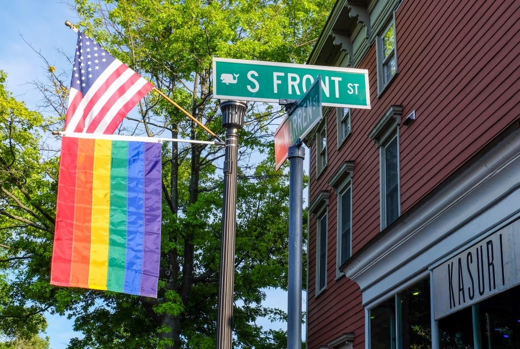 A street sign reading S Front St next to two flags: American and Pride.