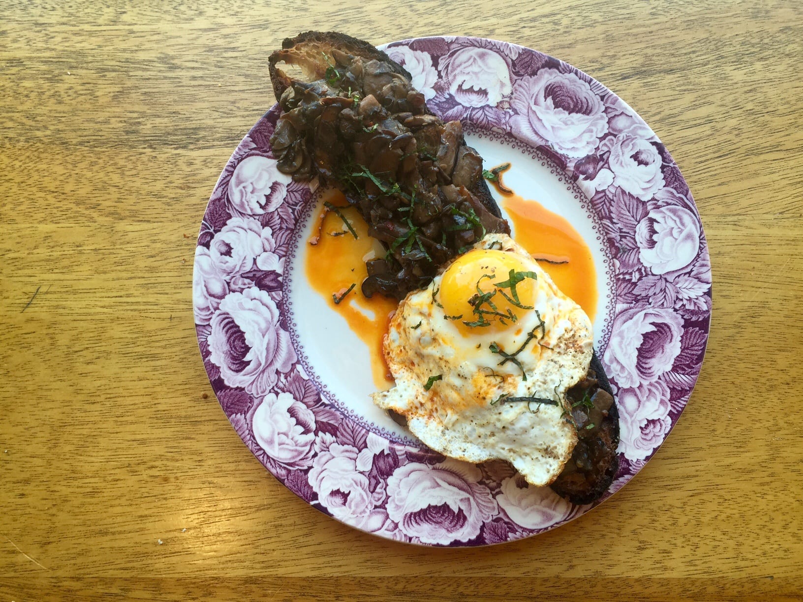 A piece of toast covered with mushrooms and a fried egg.