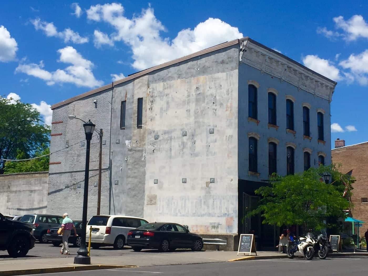 A gray and blue industrial building with pretty curved windows in front.