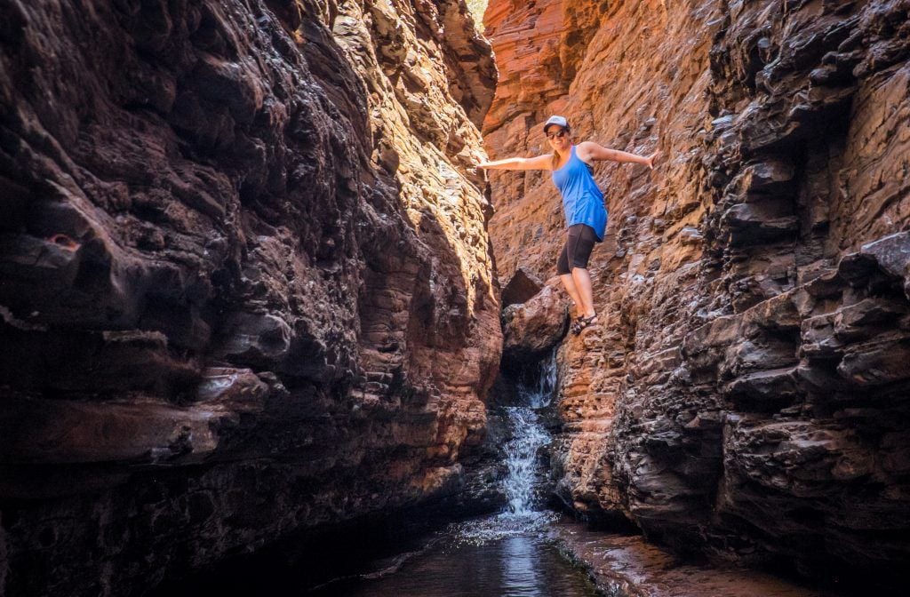 Kate "spider-walking" in a narrow opening in Karijini National Park in Western Australia, holding her body high up wedged between two walls.
