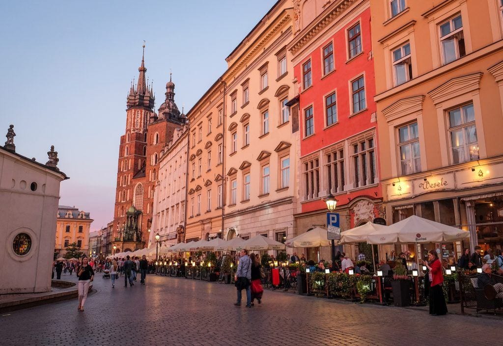 A row of buildings in Krakow, Poland, lit up with a pink tinge at sunset, ending with a church tower.
