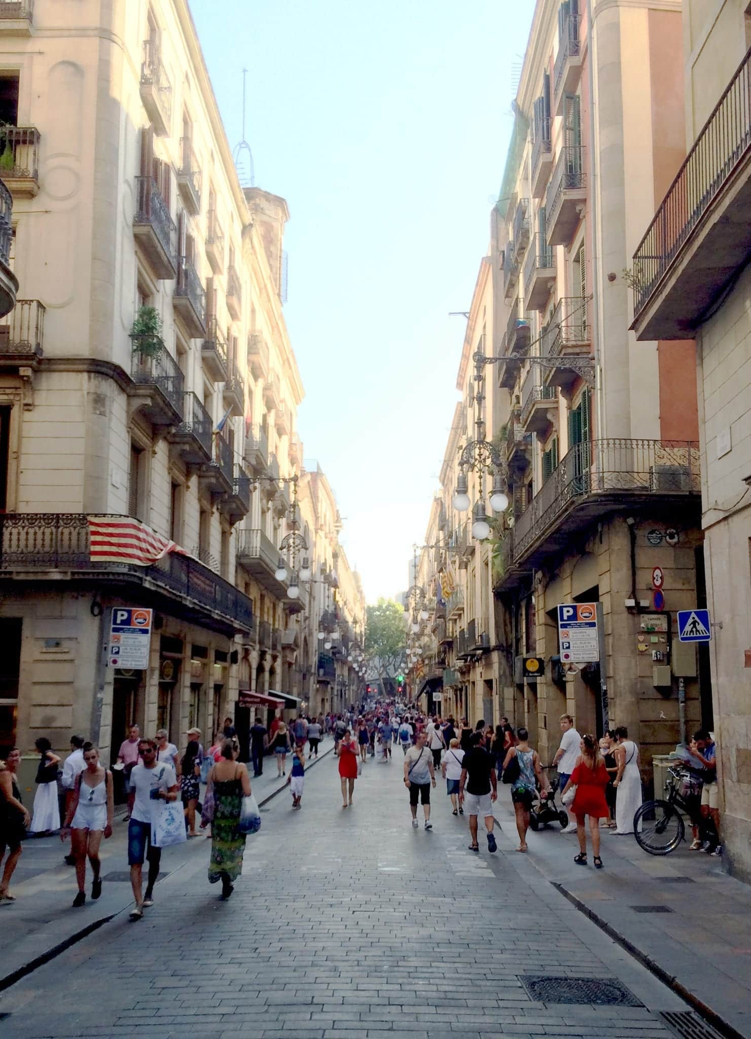 People walking down a pedestrian-only cobblestone street in El Raval, Barcelona.