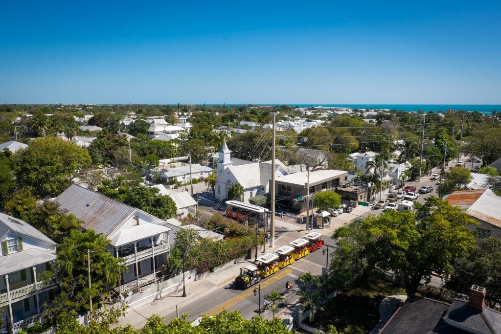 View from the Key West Lighthouse: rows of immaculately built houses interspersed with vegetation, leading to the sea.