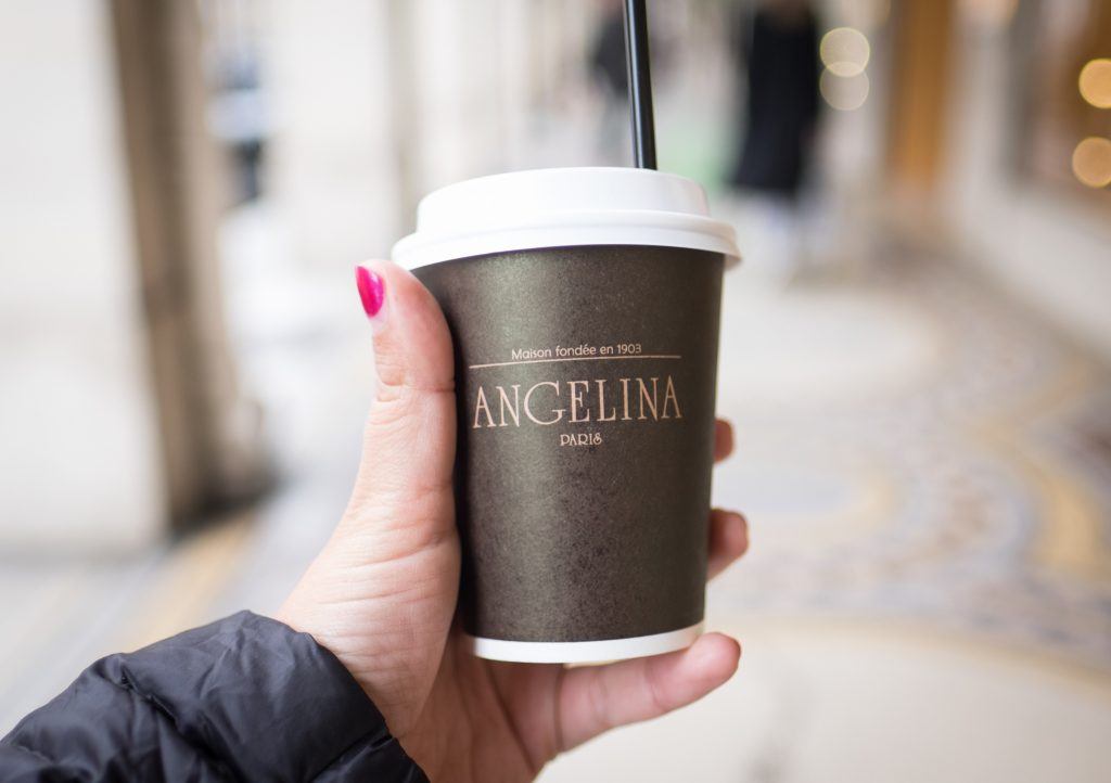 A hand holding a paper cup with "Angelina" written on it.
