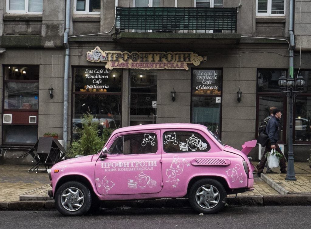 A pink car in front of a gray building in Odessa, Ukraine.