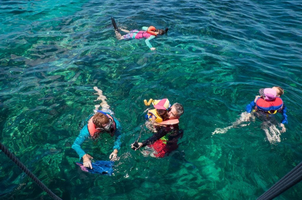 Quatre plongeurs avec masque et tuba dans l'eau bleu sarcelle du parc d'État de Pennekamp à Key Largo.