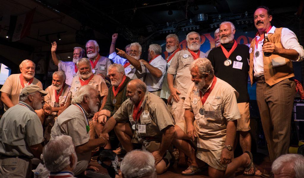 Around 12 Hemingway lookalikes, with white beards, dressed in khaki shorts, on stage at the Hemingway lookalike contest in Key West!