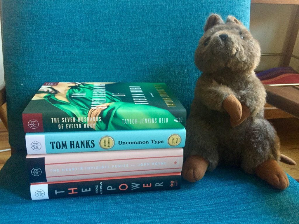 Kalbarri the stuffed Quokka next to a pile of books.