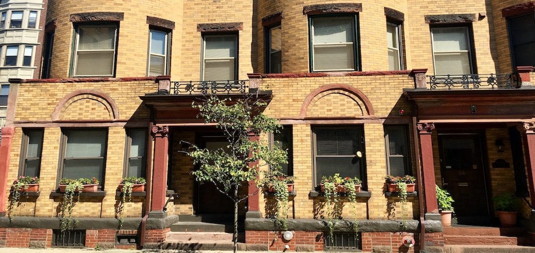 A yellow brick building with red trim on a Boston street.