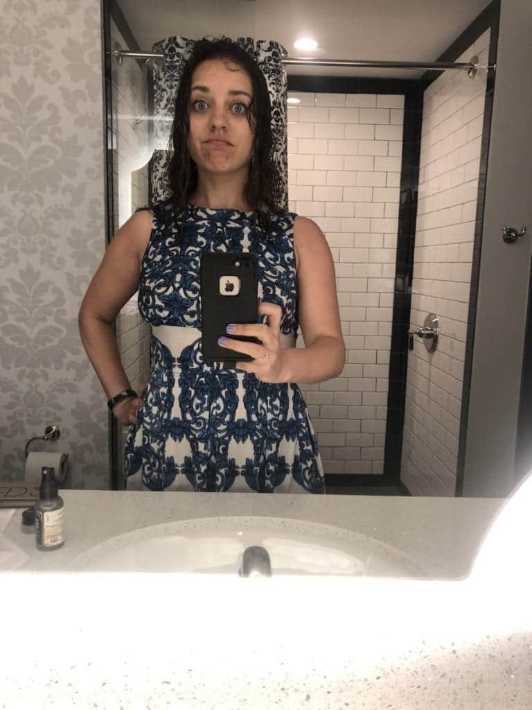 Kate taking a mirror selfie, wearing a blue and white patterned dress -- she is drenched down to her bones, including wet long curly hair, after a spring through New Orleans in the rain.