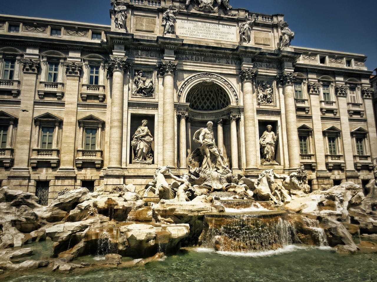 The Trevi Fountain, covered with Baroque era white marble statues and flowing water.