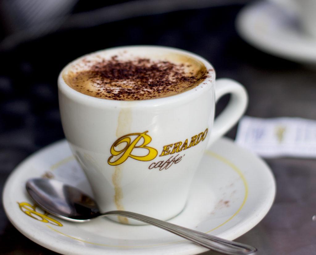 A white ceramic cup filled with espresso and milk, dusted with chocolate on top.