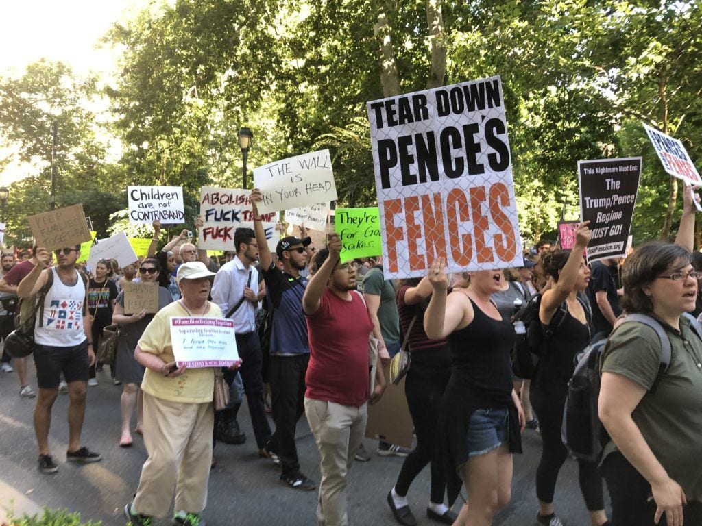 Protestors in Philadelphia holding signs, one says "Tear down Pence's Fences."