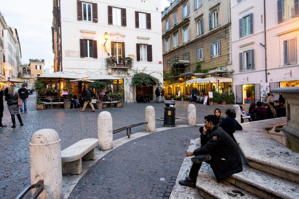 A man sitting at the base of a fountain in Monti, Rome.