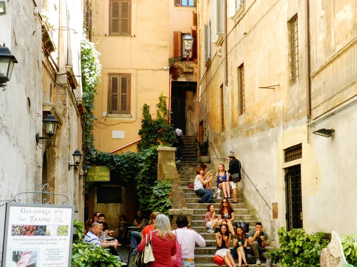 Groups and families sitting on a narrow staircase in Rome's Centro Storico.