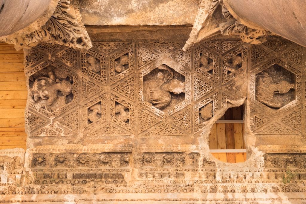 The ceiling of one of the temples in Baalbek: an intricate carved pattern in the sandstone, some parts eroded away, some of the missing parts replaced with wooden boards.