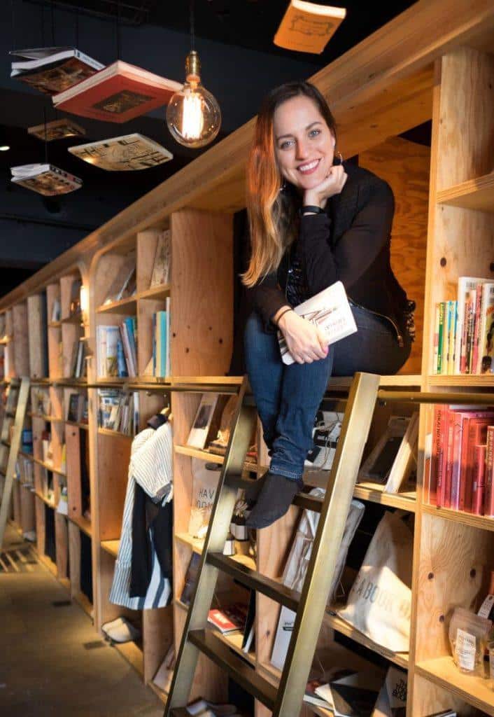 Kate sits at the top of a ladder amongst bookshelves that double as dorm beds at the Tokyo Book and Bed Hostel.