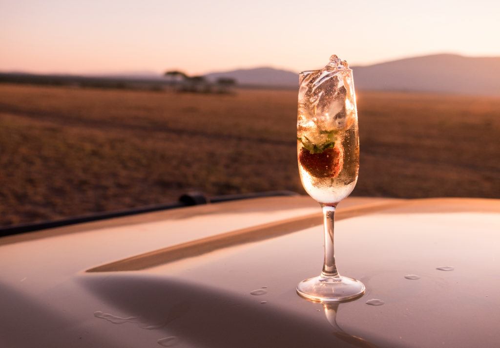 A strawberry slowly dropping into a glass of champagne at sunrise.