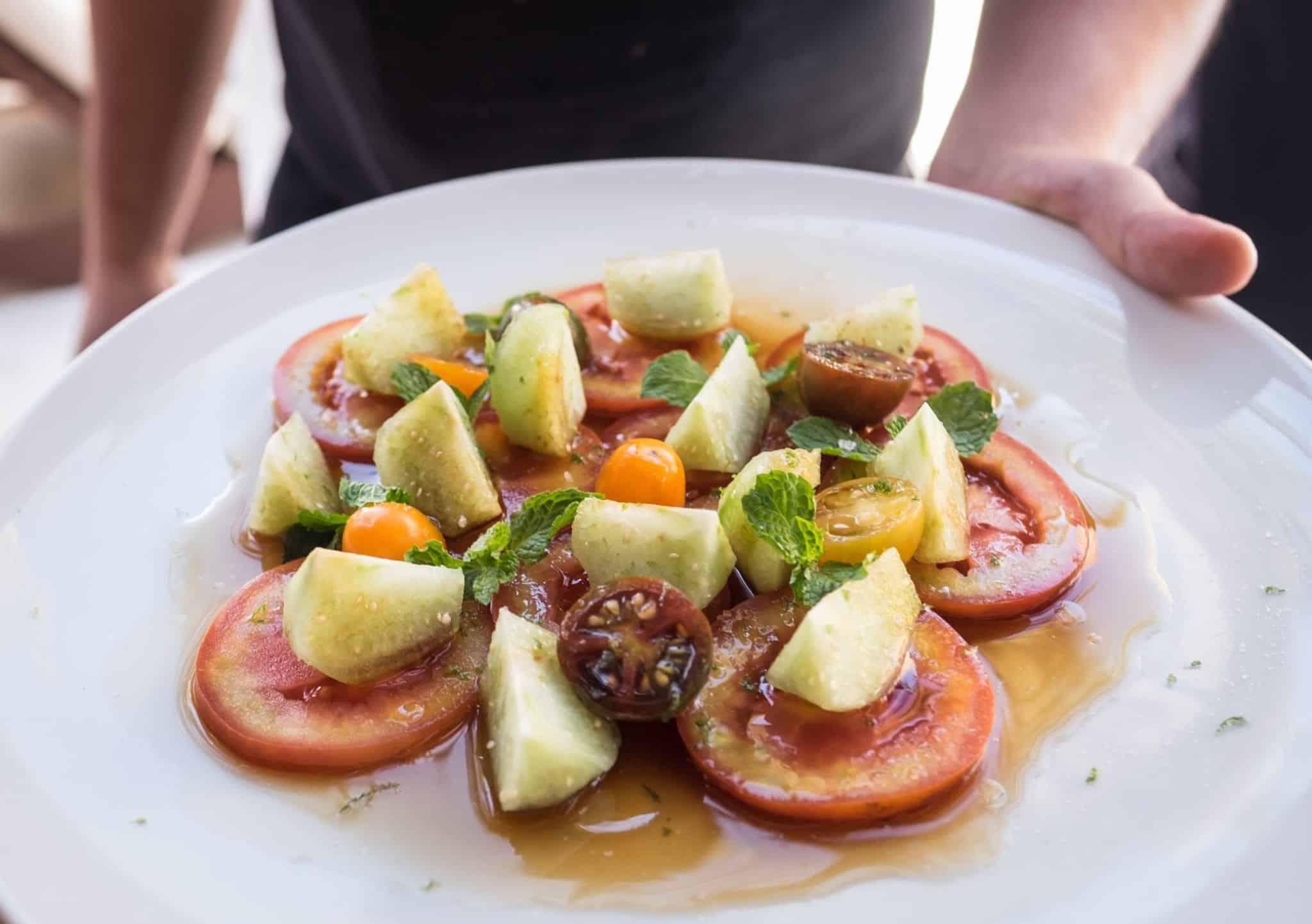 Marinated tomatoes and cucumbers on a white plate.