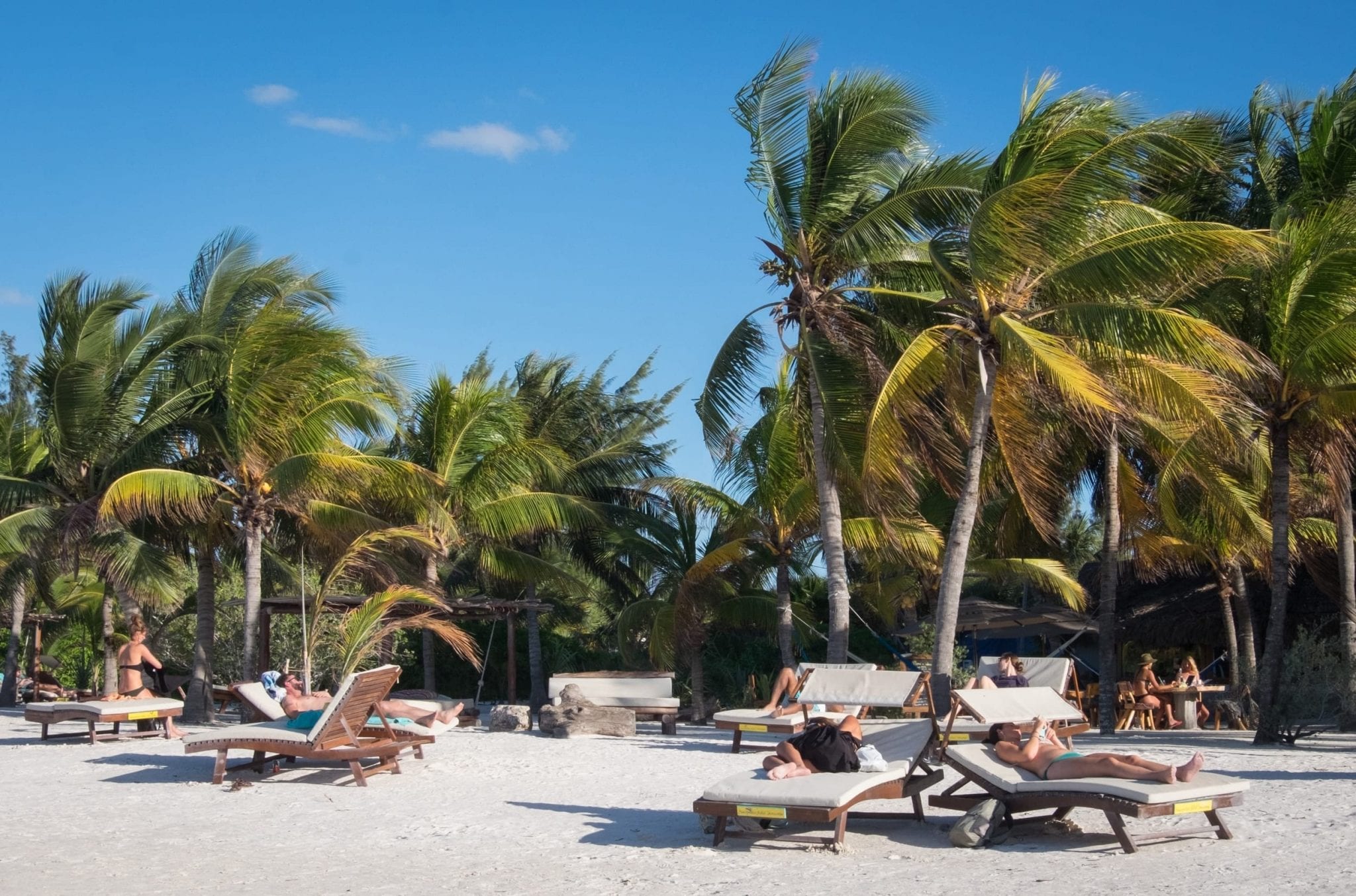 People relaxing on lounge chairs on the beach.