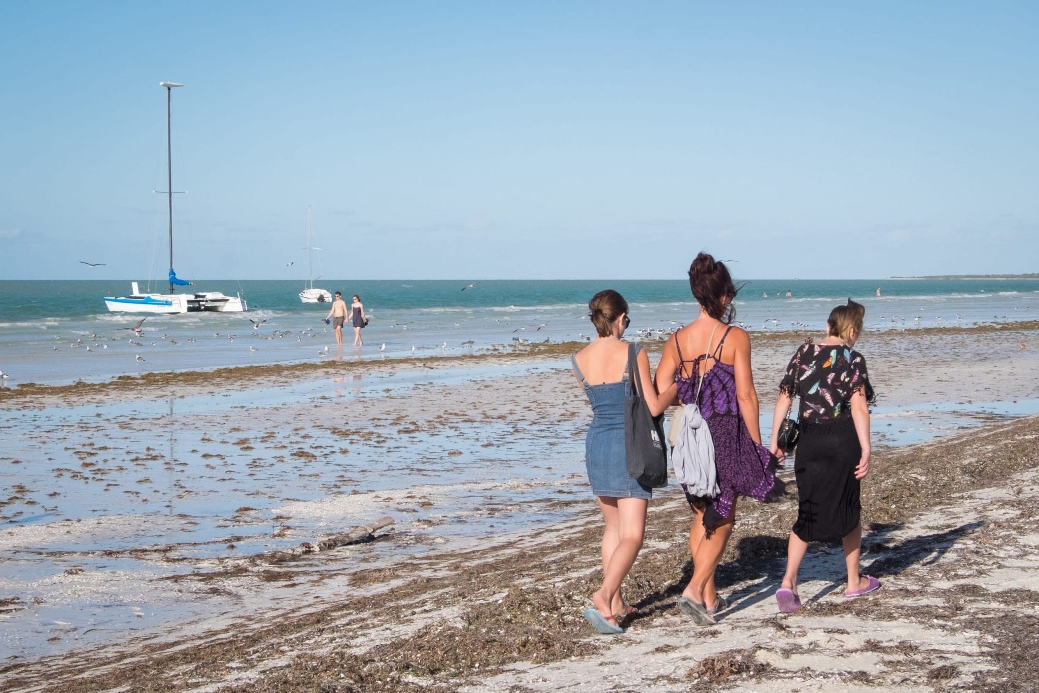 Three women walking along with beach.