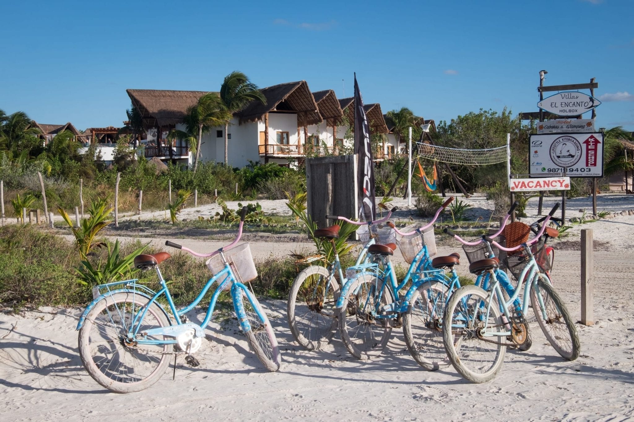 Several bikes on the beach near some villas.