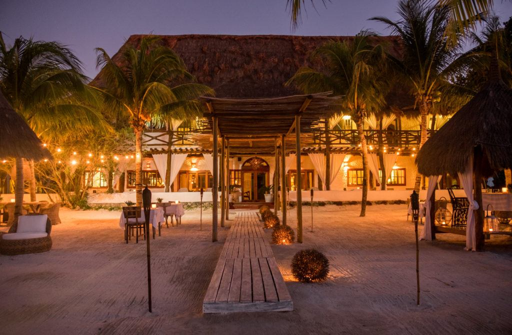 Casa Sandra, with its white walls and thatched roof, lit up at night