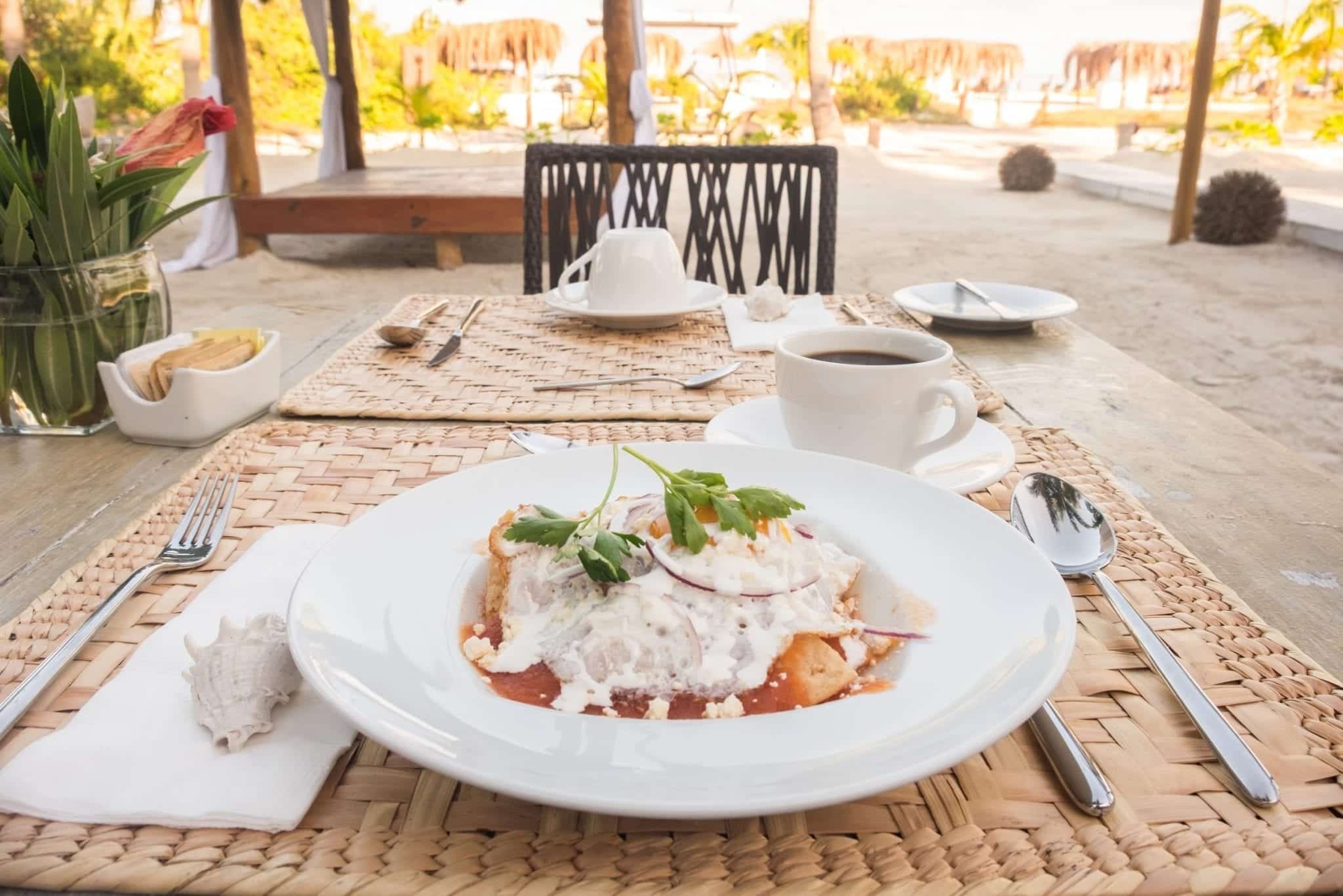 Table with a plate of food and cup of coffee, looking out over the beach.