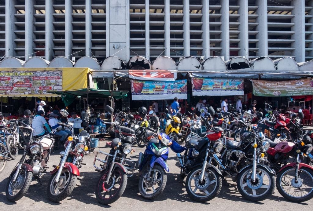 Motorcycles lined up in a row, parked outside a building in Merida, Mexico.