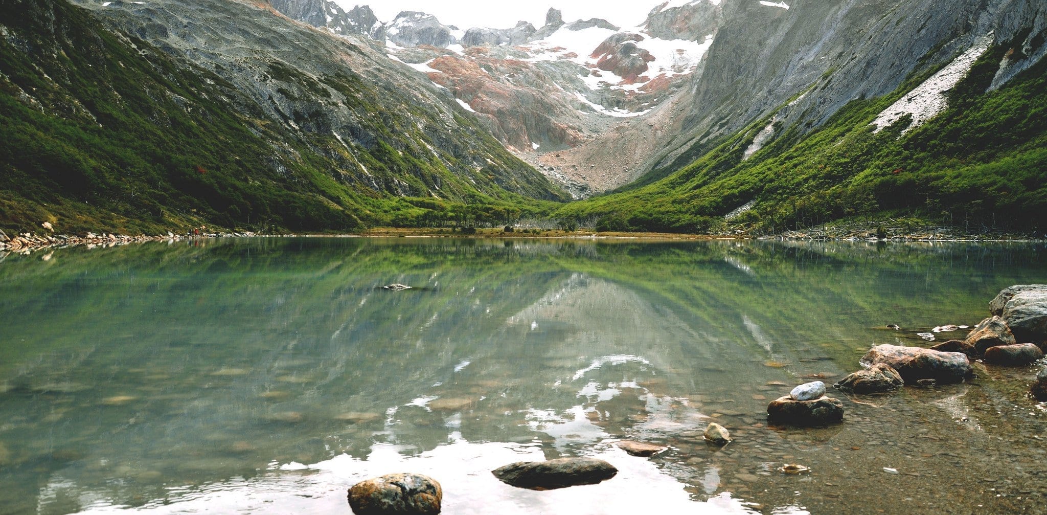 A reflective green lake set amongst mountains.