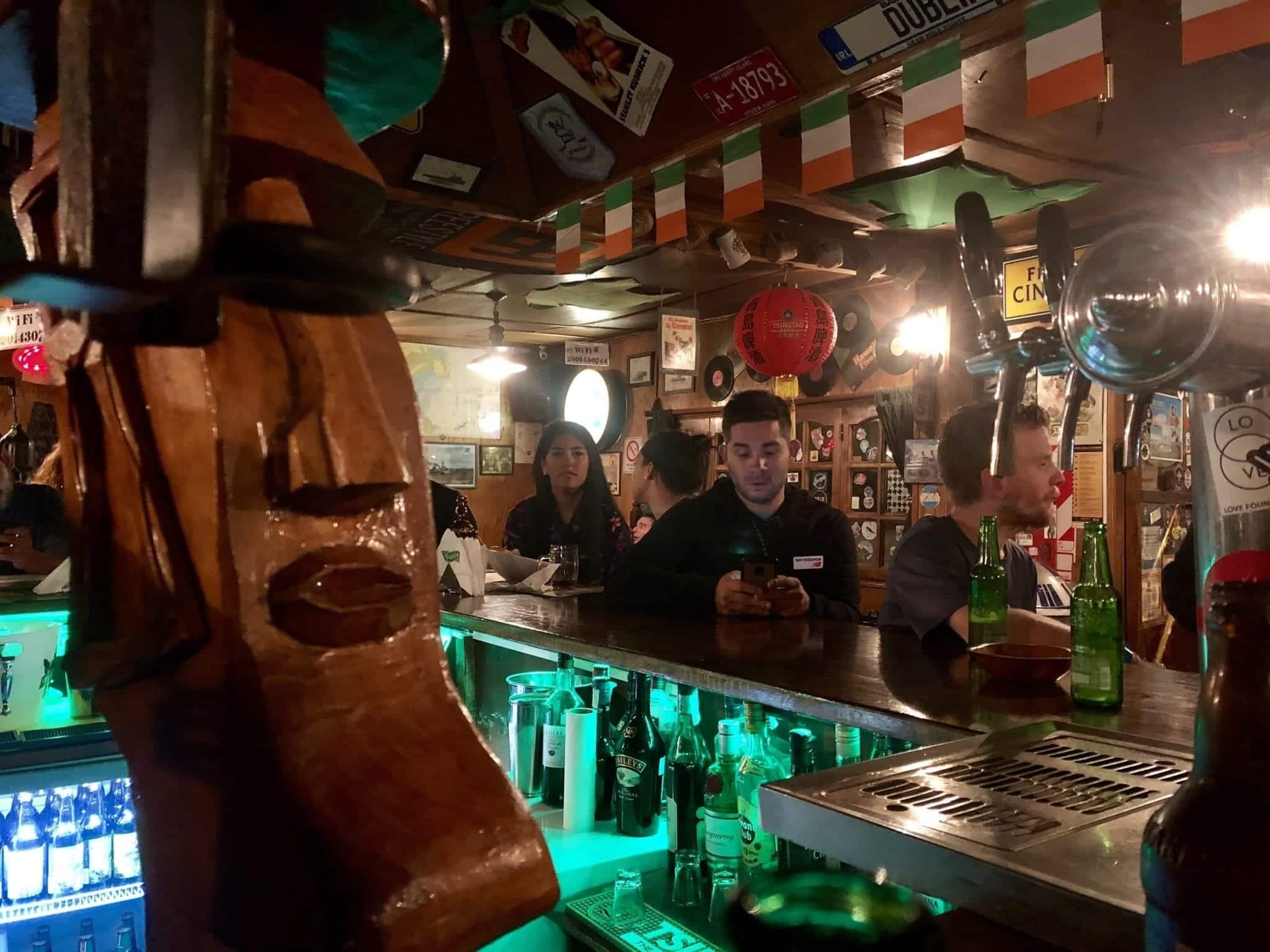 People sitting at the bar in an Irish pub, drinking beers.