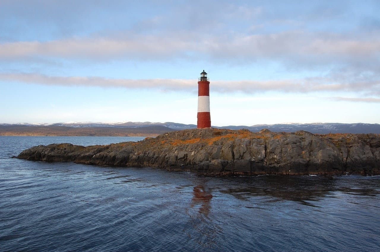 A red and white lighthouse perched on a rocky outcropping.