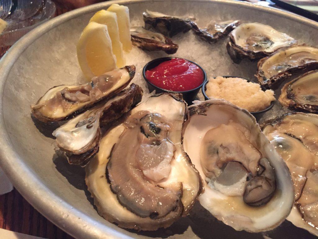 A plate filled with ice, oysters and lemon wedges on top.