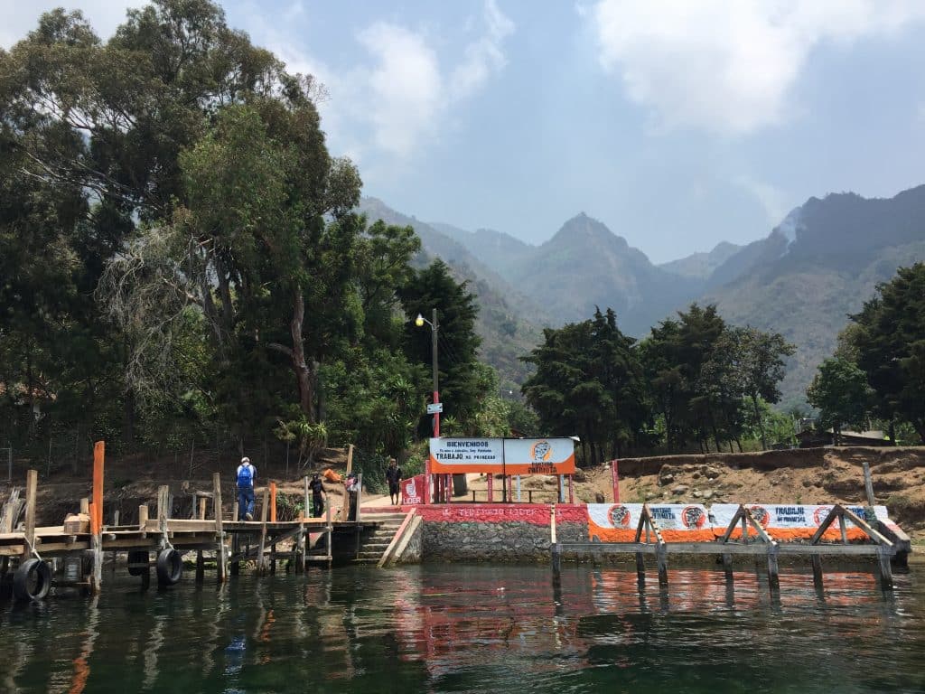 Colorful wooden docks on the edge of Lake Atitlan, with mountains rising in the background.
