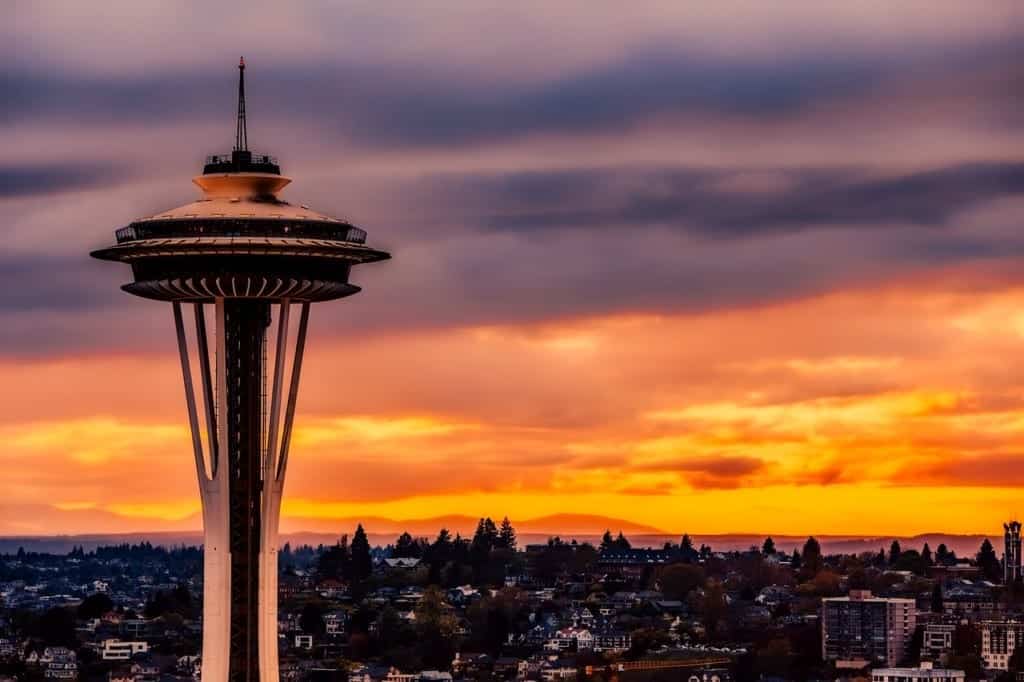 The Space Needle lit up with an orange and purple sunset behind it.