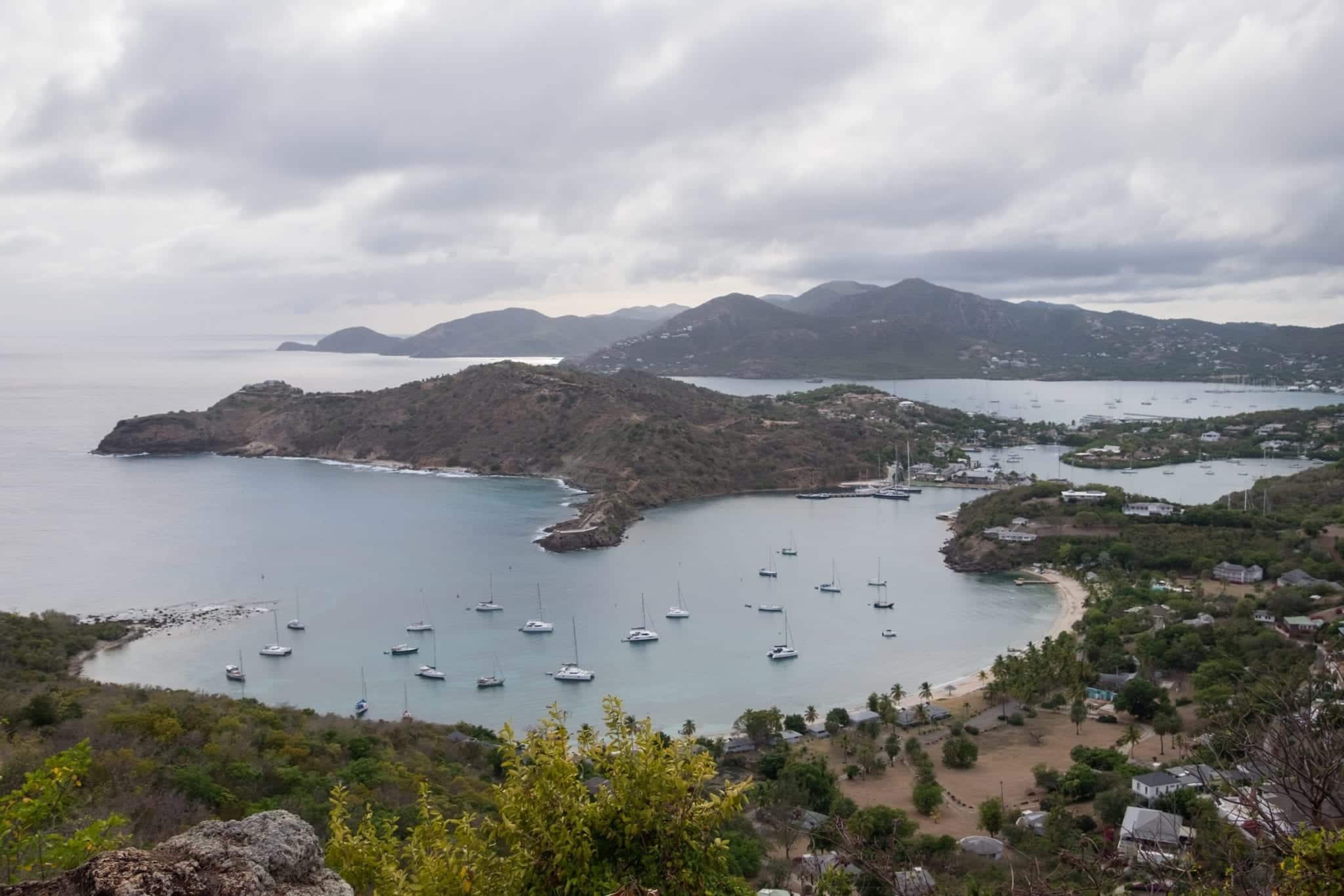 View over the English Harbor from above at Shirley Heights -- pieces of land jutting together and several sailboats in the water.