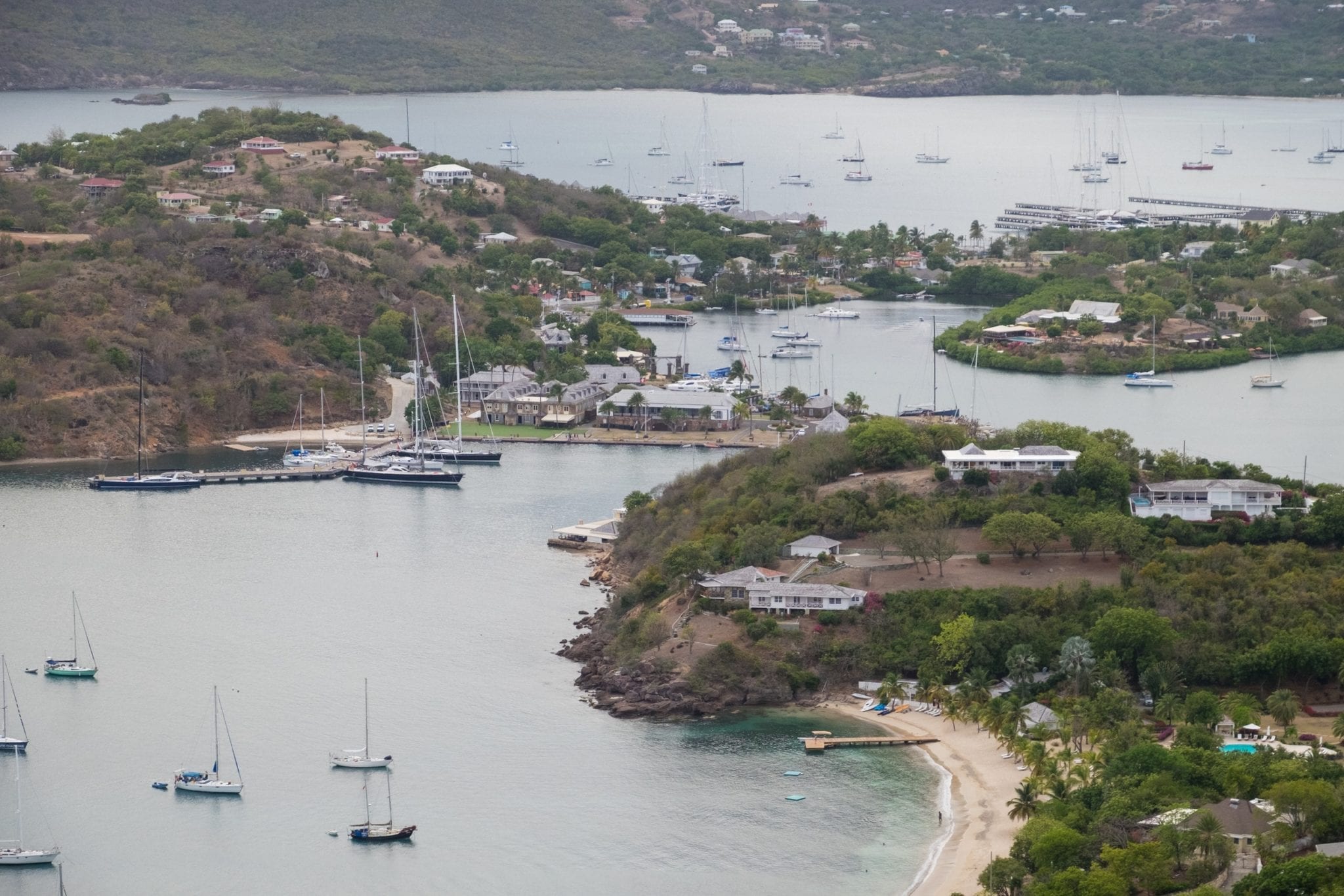 View over the English Harbor from above at Shirley Heights -- pieces of land jutting together and several sailboats in the water.