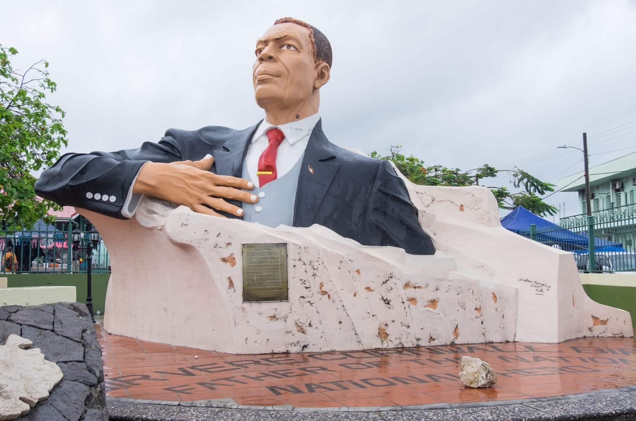 Giant colored of the first president of Antigua, from the chest up in a suit coming out of a piece of rock in the center of town