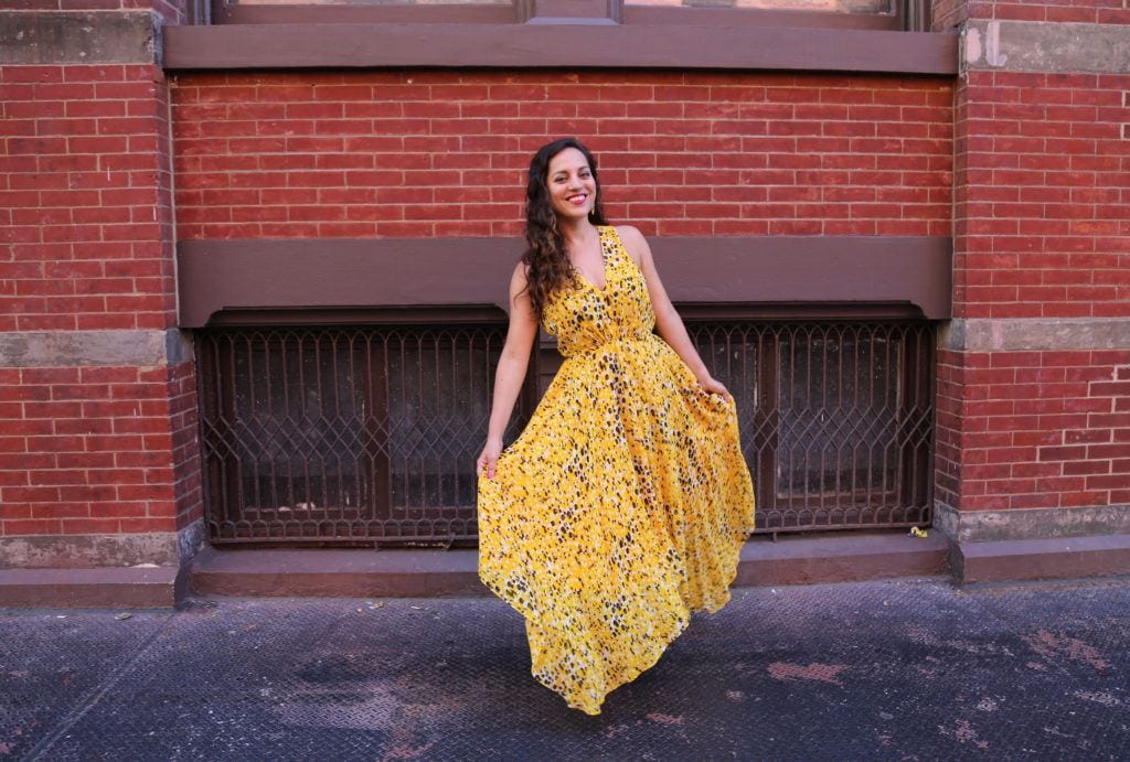 Kate wearing a big yellow gown in front of a brick wall in SoHo, NYC.