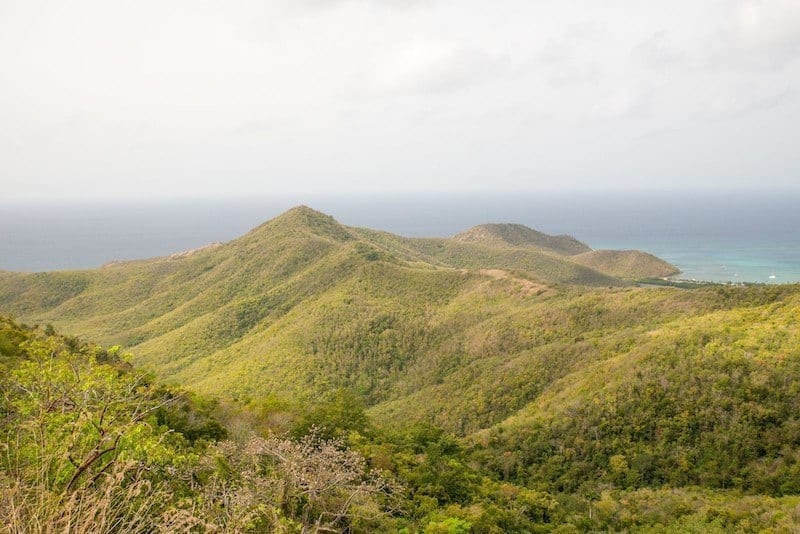 Signal Hill in Antigua -- several green pointy hills in front of a blue-gray ocean horizon.