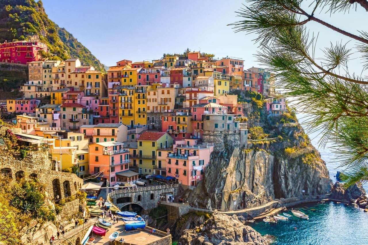 One of the villages of Cinque Terre, Italy: a village of brightly colored houses, stacked on top of each other, built on a cliff leading down into the sea.